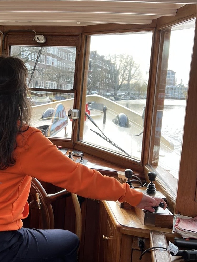 A skipper at the wheel in a wooden boat cabin