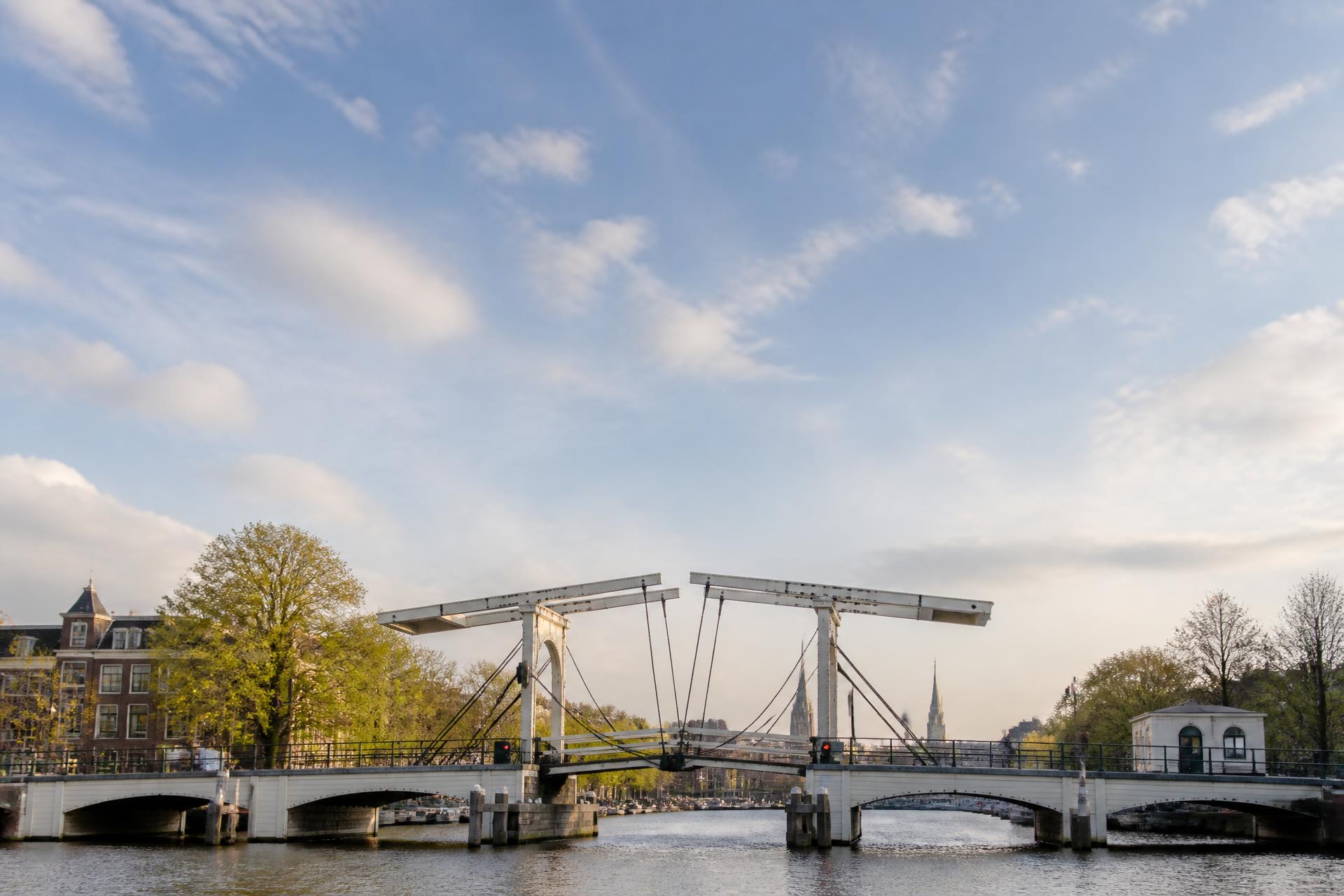 Een klassieke witte ophaalbrug over een Amsterdamse gracht in het late middaglicht