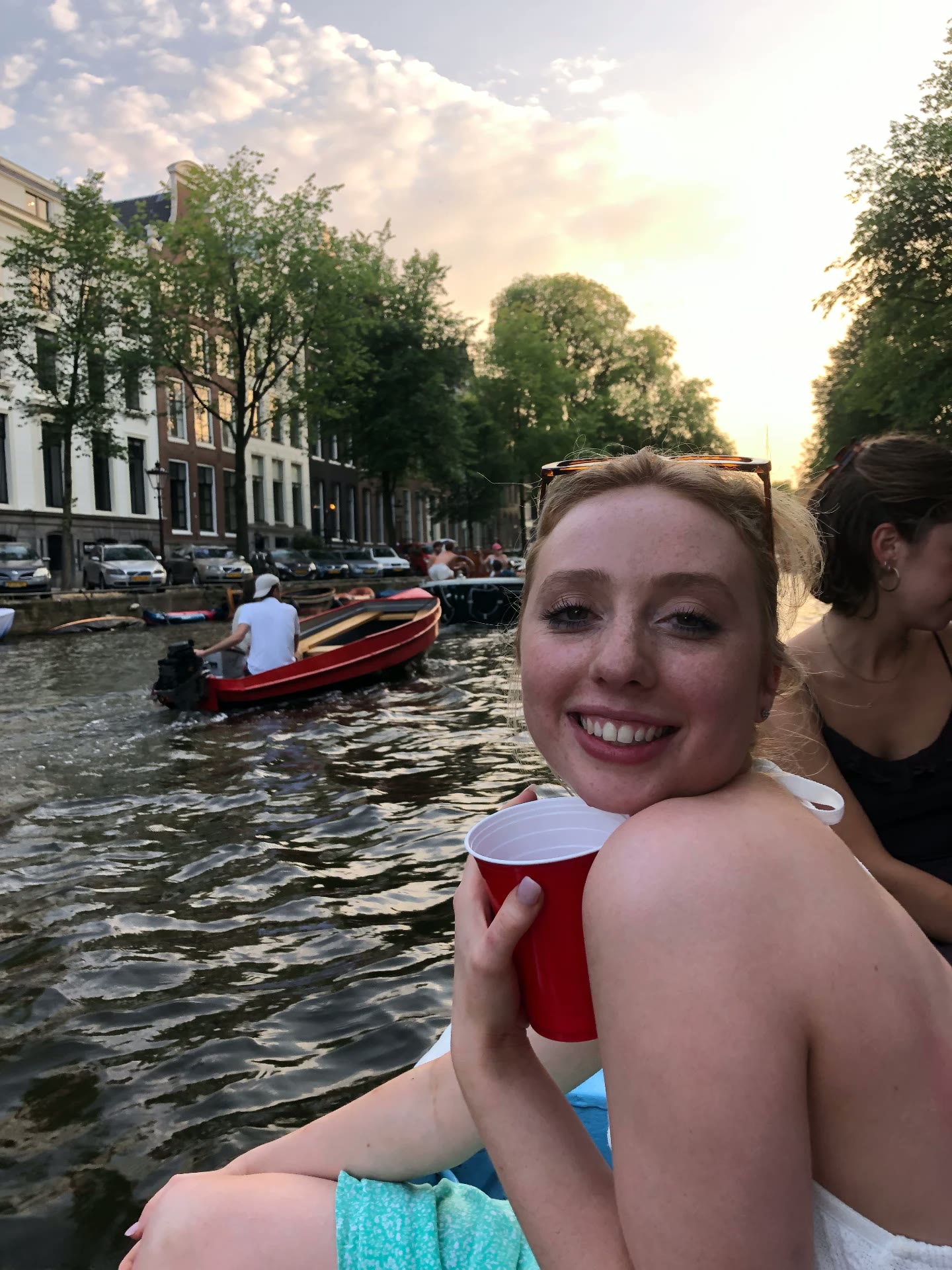 A friend on the boat at sunset, another boat passing behind her